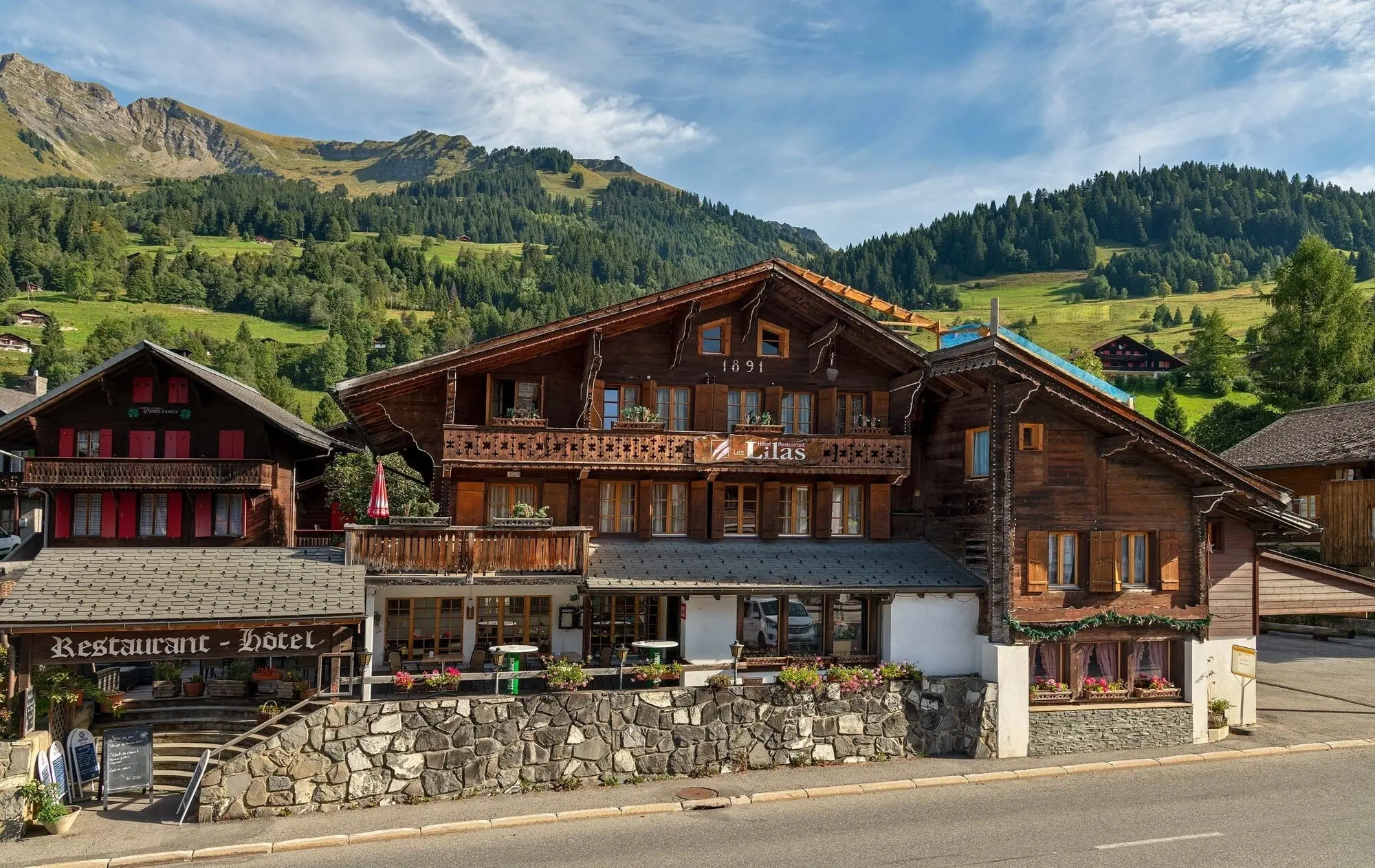 The chalet hotel below green mountains in summer