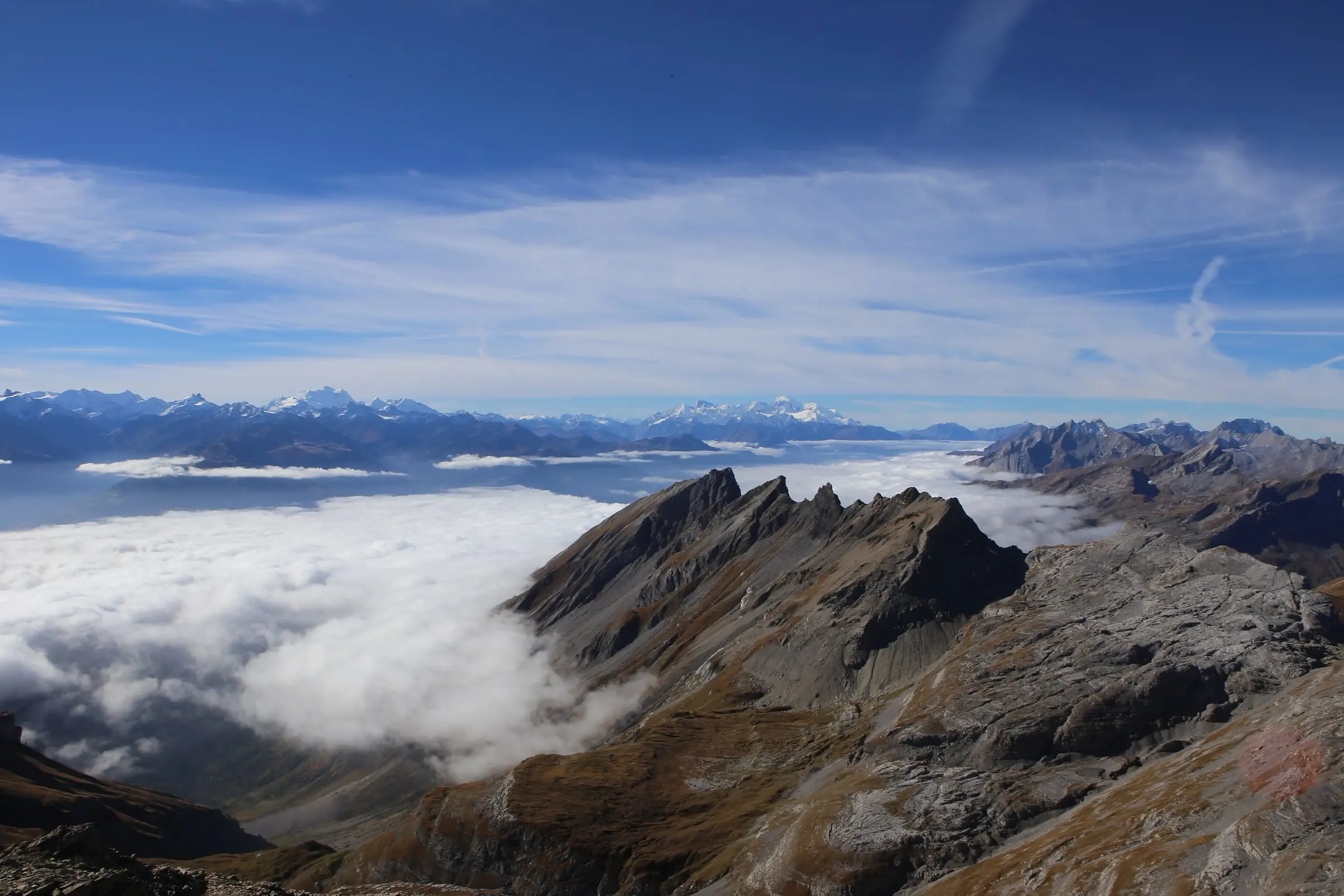 Sea of clouds filling valleys below rocky ridges